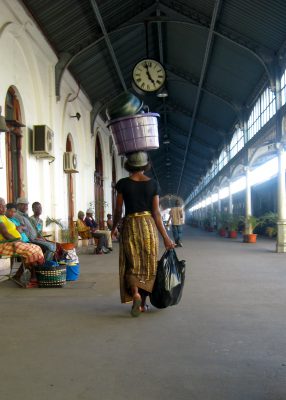 Woman walking in Africa balancing goods and buckets on her head