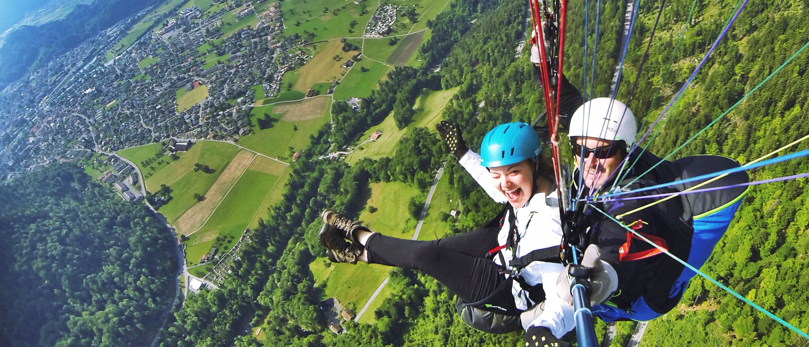 Two people skydiving over green pastures