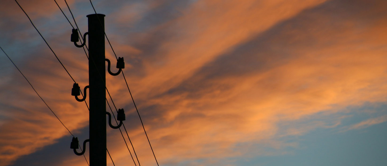 Telephone pole against orange sky
